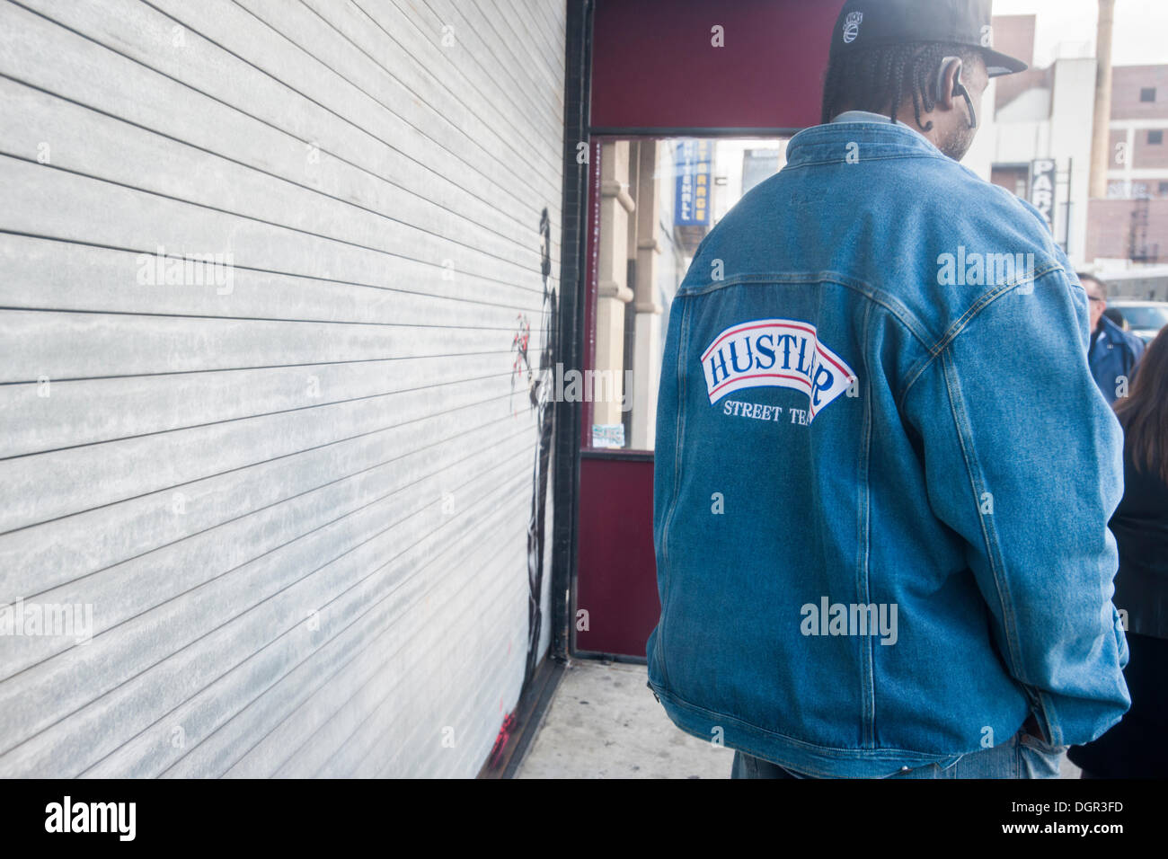 New York, NY, USA. 24. Oktober 2013. Street-Art-Fans strömen in Flynts Hustler Club im Stadtteil "Hells Kitchen" von New York auf Donnerstag, 24. Oktober 2013, "Waiting in vain" der vierundzwanzigste Ausgabe von Banksy-Graffiti-Kunst zu sehen. Die Schablone Darstellung ist auf das Rollup-Tor am Eingang der Gentlemen Club, das Sicherheitspersonal außerhalb entsandt hat, um ihr neues Meisterwerk zu schützen.  Die schwer fassbare Streetart-Künstler schafft Werke rund um die Stadt jeden Tag im Laufe des Monats Oktober "Besser aus als In" genannt.  (© Richard B. Levine) Bildnachweis: Richard Levine/Alamy Live N Stockfoto