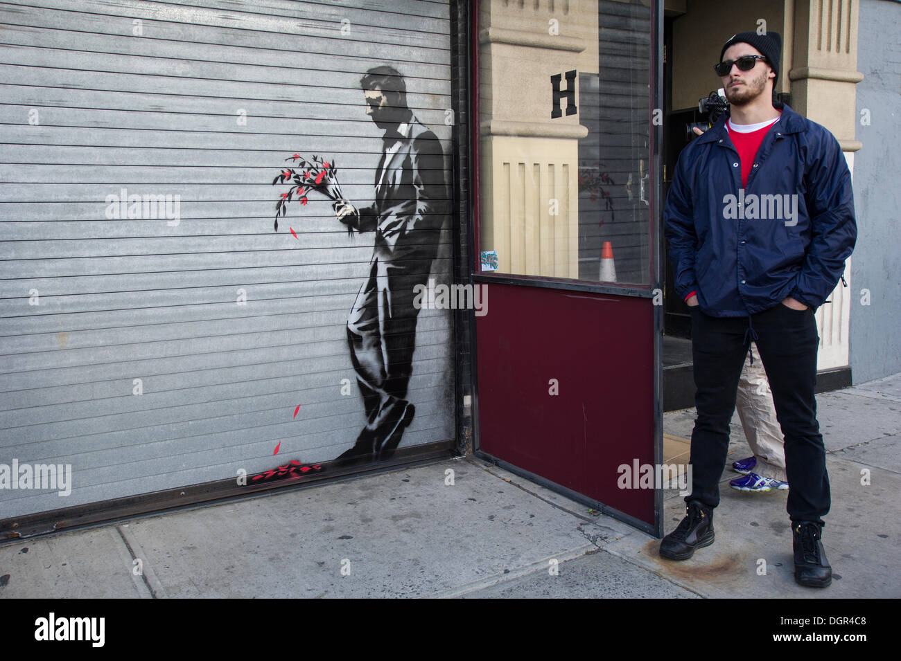 Street-Art-Fans strömen in Flynts Hustler Club im Stadtteil "Hells Kitchen" von New York auf Donnerstag, 24. Oktober 2013, "Waiting in vain" der vierundzwanzigste Ausgabe von Banksy-Graffiti-Kunst zu sehen. Die Schablone Darstellung ist auf das Rollup-Tor am Eingang der Gentlemen Club, das Sicherheitspersonal außerhalb entsandt hat, um ihr neues Meisterwerk zu schützen.  Die schwer fassbare Streetart-Künstler schafft Werke rund um die Stadt jeden Tag im Laufe des Monats Oktober "Besser aus als In" genannt.  (© Frances M. Roberts) Stockfoto