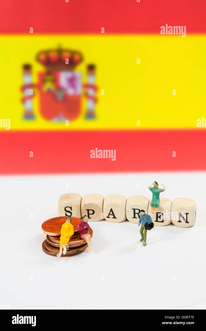 Miniaturen auf Münzen, "rettet Würfel Buchstaben bilden das Wort" vor der spanischen Flagge, symbolisches Bild für das Sparprogramm Stockfoto