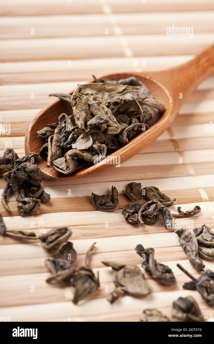 Getrocknete Blätter von grünem Tee über Löffel. Flachen DOF, Fokus auf Blätter im Löffel. Stockfoto