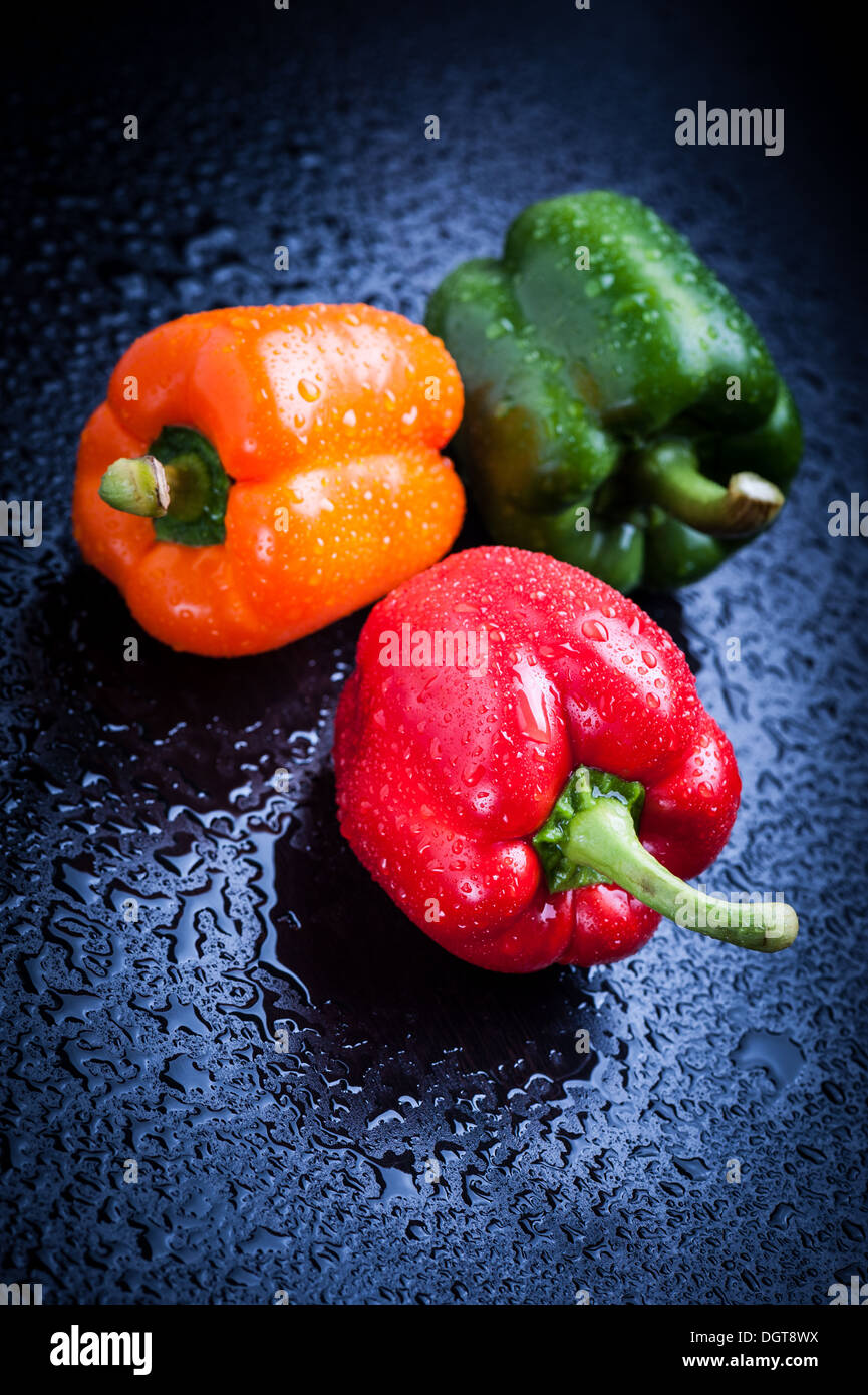 Orange, rote und grüne Paprika auf blaue Tabelle nach Regen Stockfoto