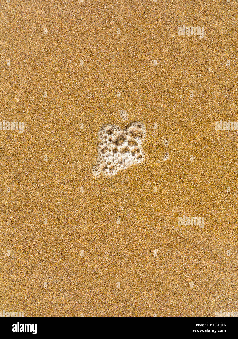 Nahaufnahme von Surf Bläschen an einem Strand nur flach Sandoberfläche und Textur zu zeigen Stockfoto
