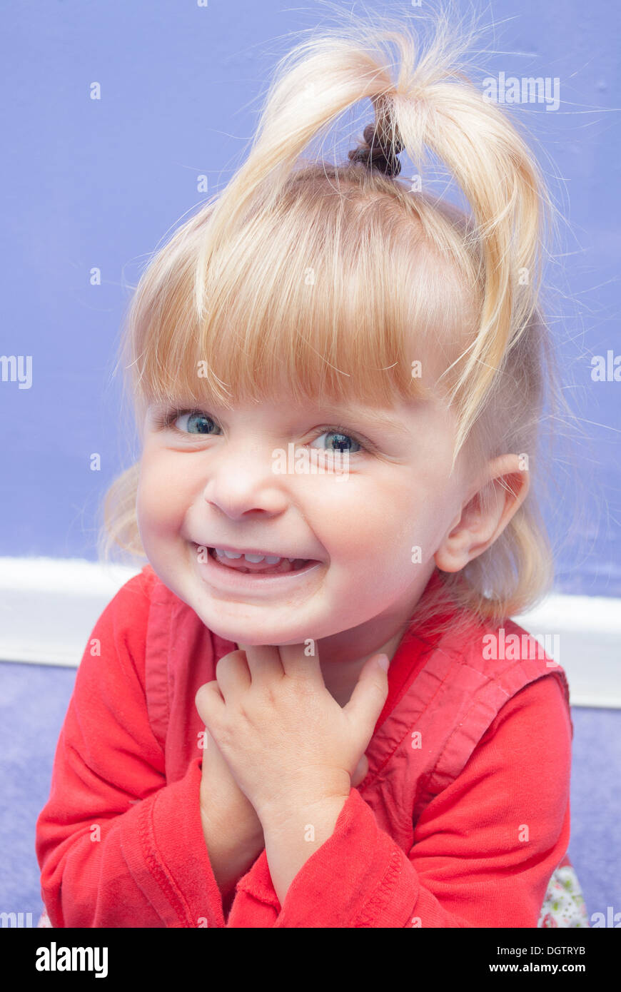 Achtzehn Monate altes Mädchen lächelte süß hält ihre Hände unter ihr Kinn. Stockfoto