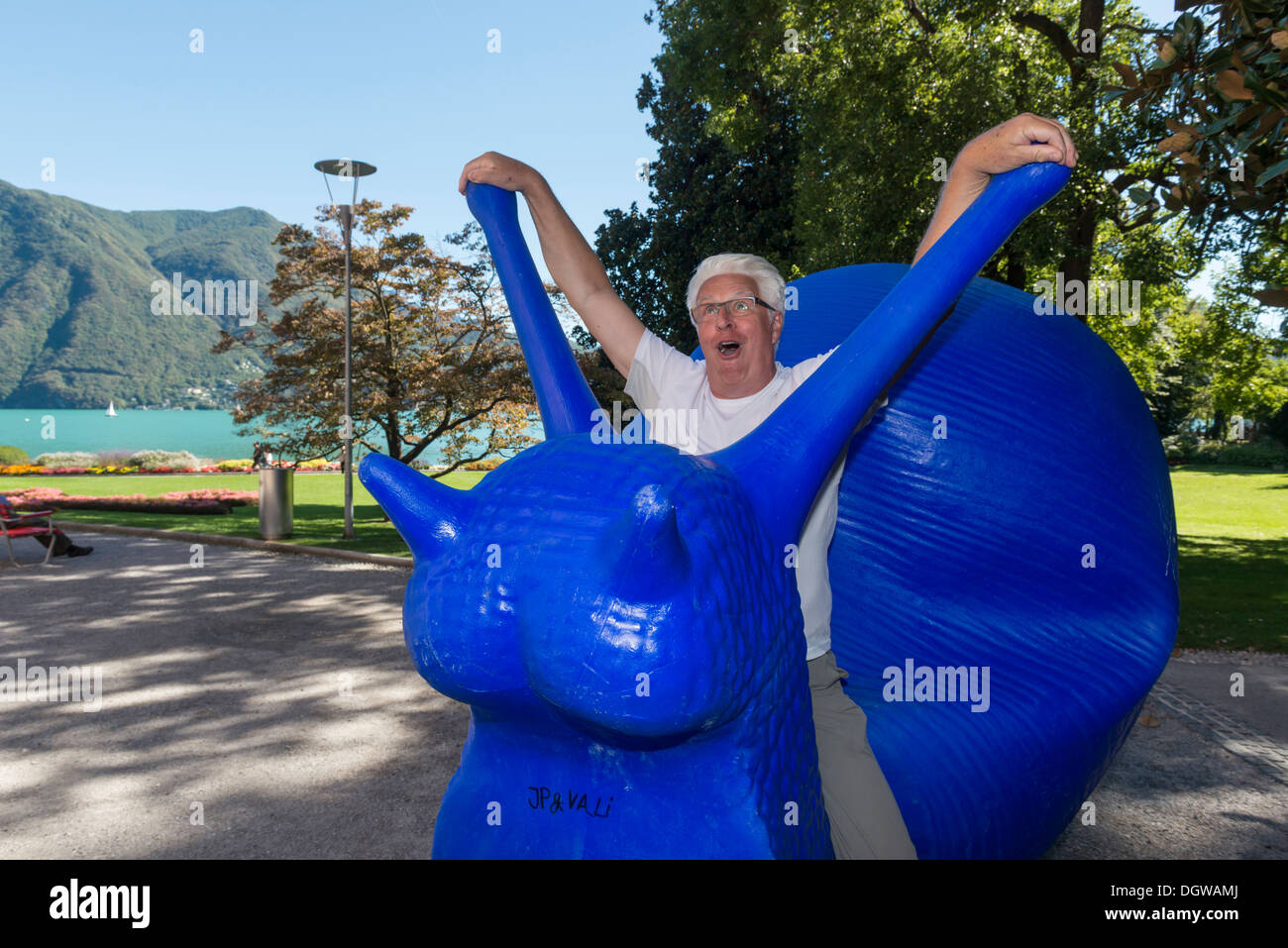 Ein Mann, der vorgibt, eine riesige blaue Schnecke Skulptur zu fahren. Lugano. Schweiz Stockfoto