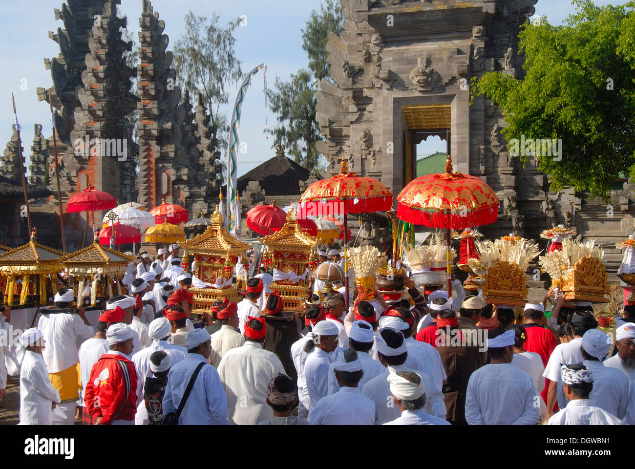 Balinesischen Hinduismus, Versammlung von Gläubigen, die Zeremonie, die Gläubigen in hellen Tempel Kleid tragen rote Sonnenschirme und Schreine, Tempel Stockfoto