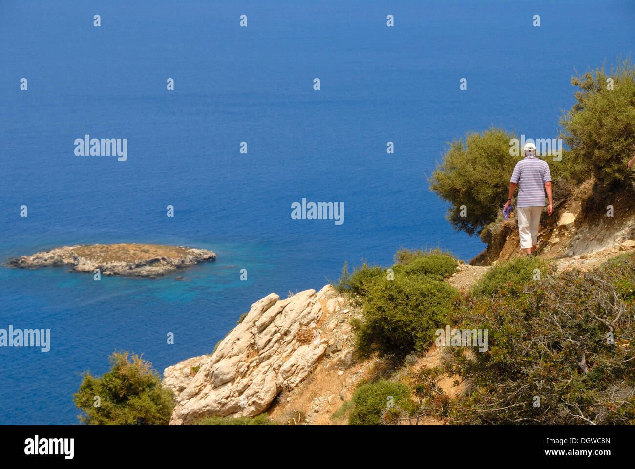 Frau auf einem steilen Felsen der Küste Weg wandern mit Blick auf eine Insel und das blaue Meer von Moutti Tis Sotiras absteigend Stockfoto