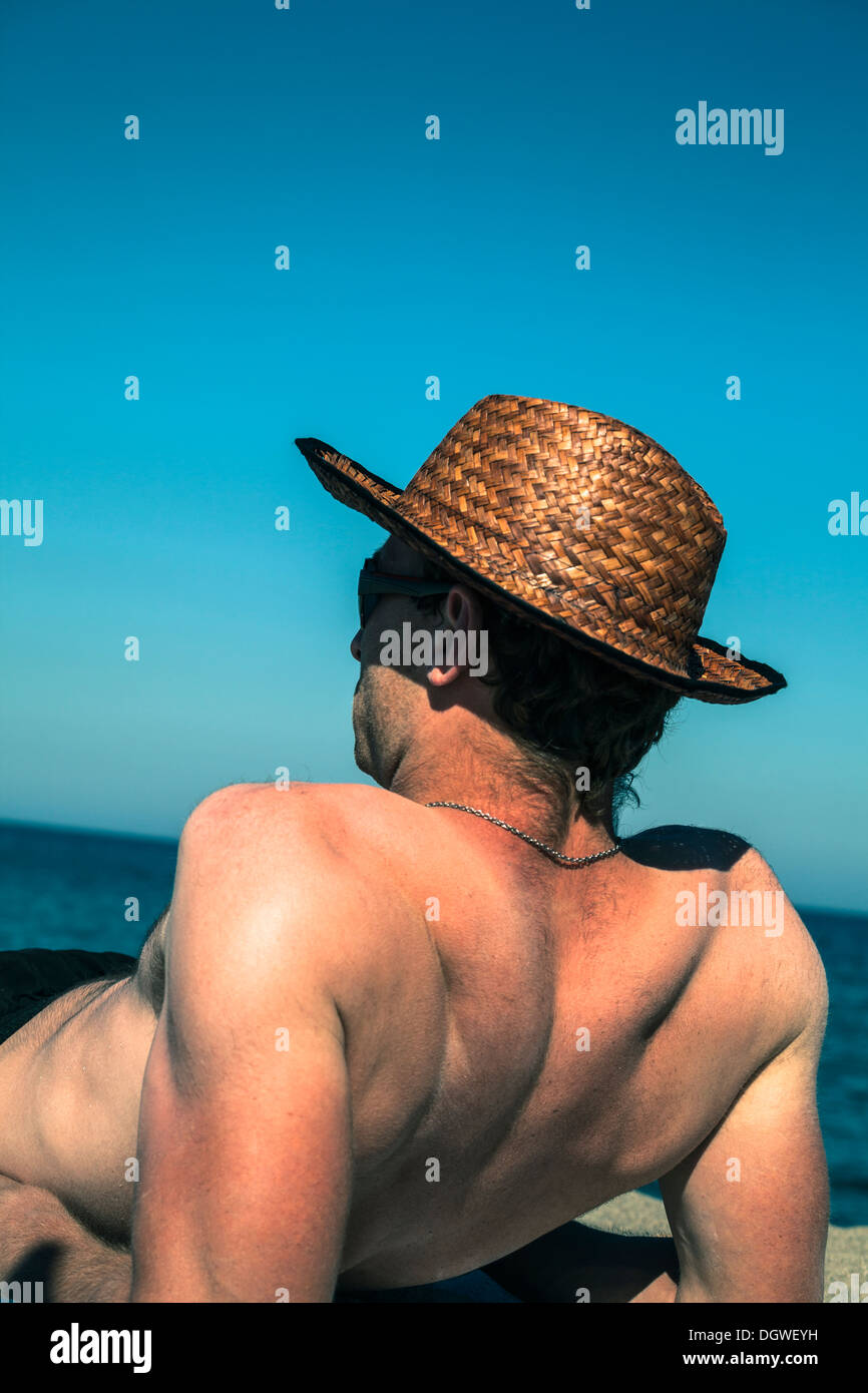 Nackter Oberkörper Mann entspannend am Strand über strahlend blauen Himmel. Stockfoto