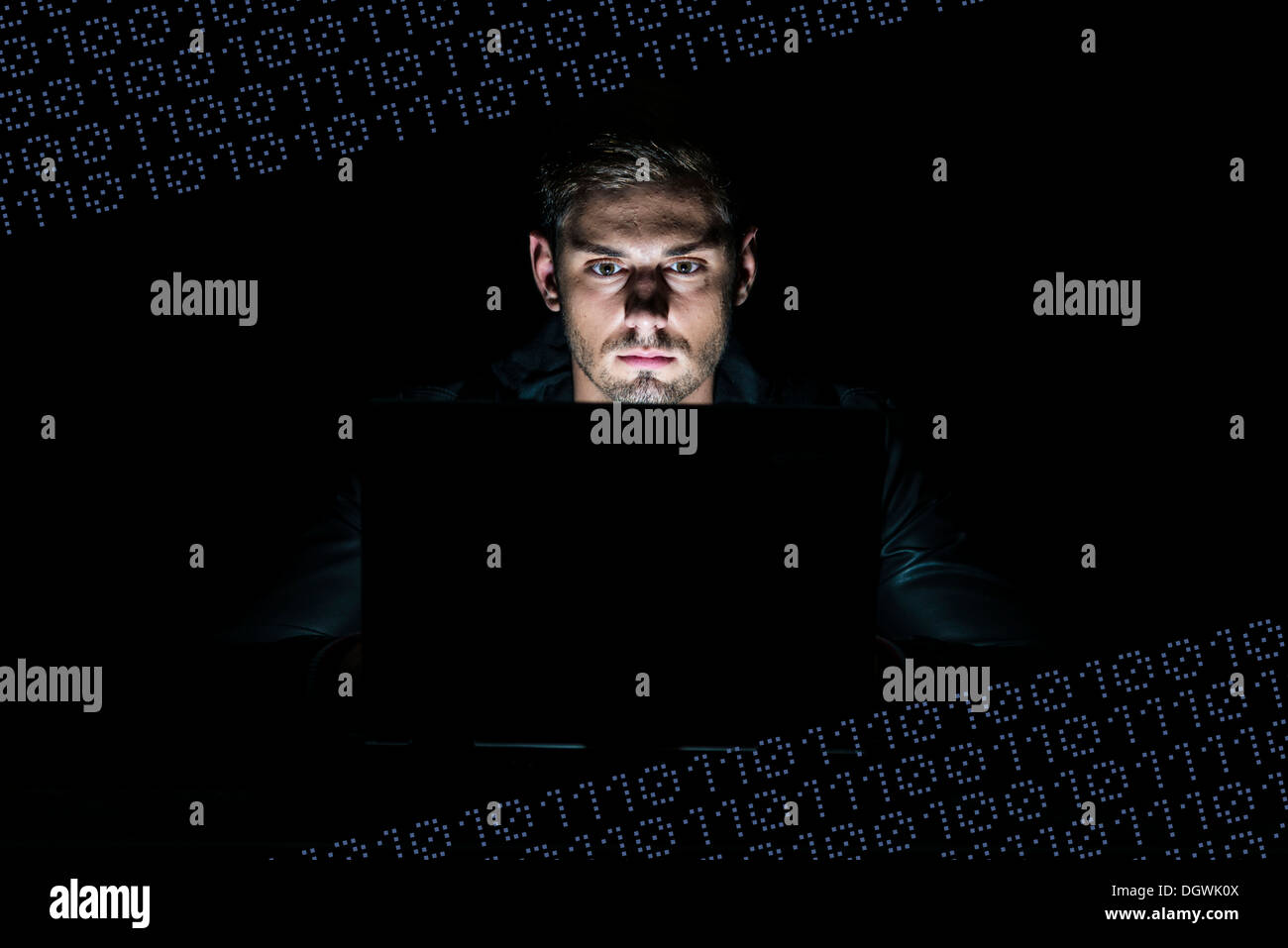 Junger Mann sitzt an einem Computer, umgeben von Binärzahlen, 0en und 1en Stockfoto