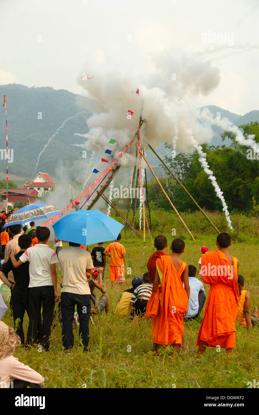 Festival, Rakete abfeuern, bang Fai, Start und die Explosion einer Rakete auf der Startrampe, Mönche in orangefarbenen Gewändern auf Stockfoto