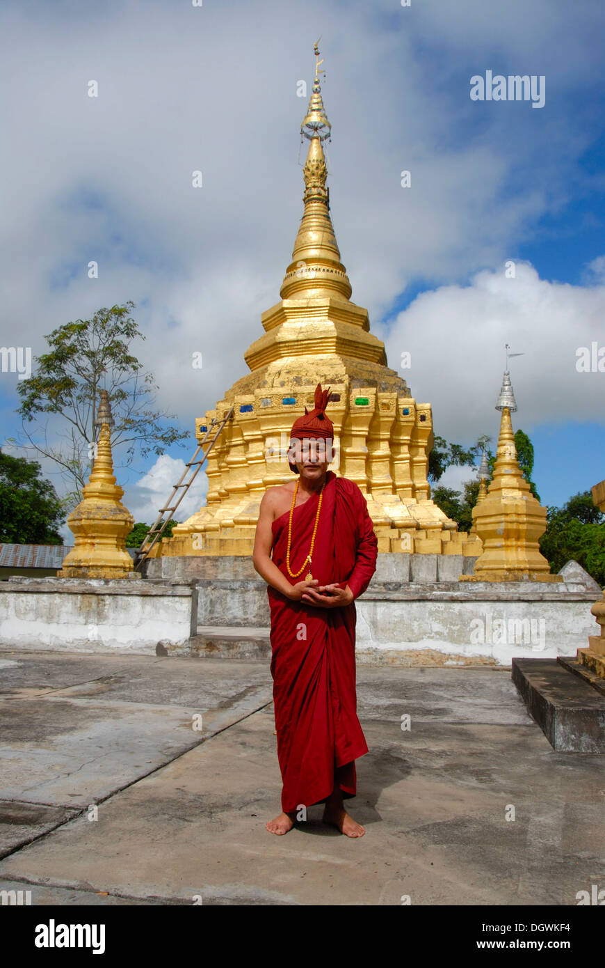 Theravada-Buddhismus, Mönch in ein rotes Gewand mit Hut, goldenen Stupa, dass Xieng Tung, Muang Sing, Luang Namtha Provinz, Laos Stockfoto