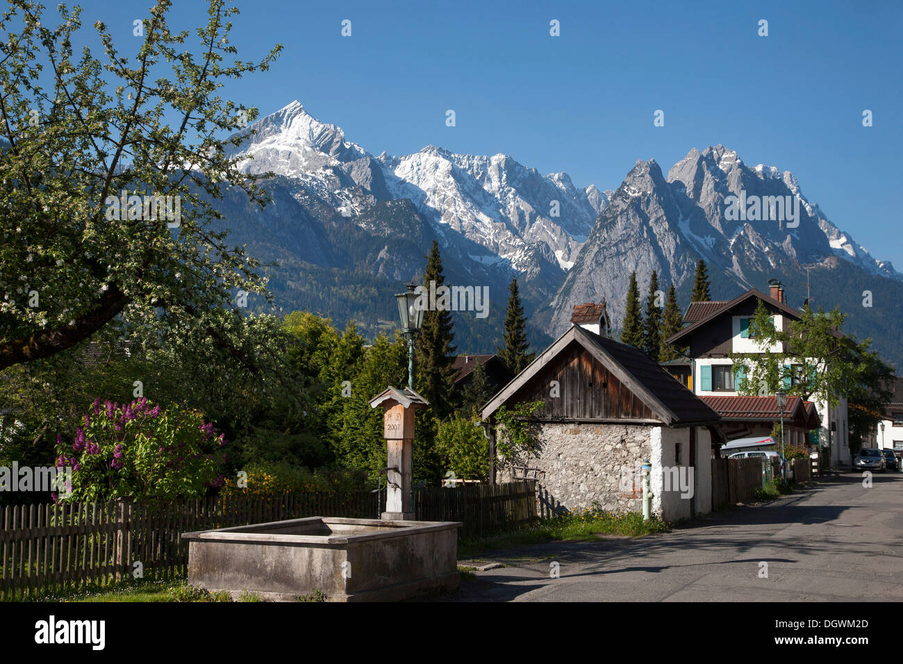 Fruehlingsstrasse, eine Straße mit alten Häusern und einem Brunnen, Wettersteingebirge, die Alpspitze Berg, die Zugspitze Berg Stockfoto