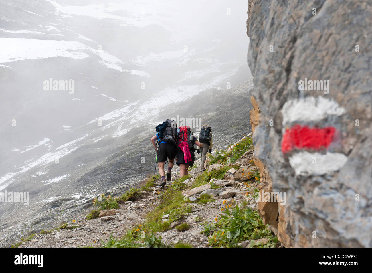 Roten und weißen Markierungen auf Steinen, tragen Wandern Wanderweg, Wanderer auf dem Weg bis zum Pass im Nebel, Pass Hohtürli Kandersteg Stockfoto
