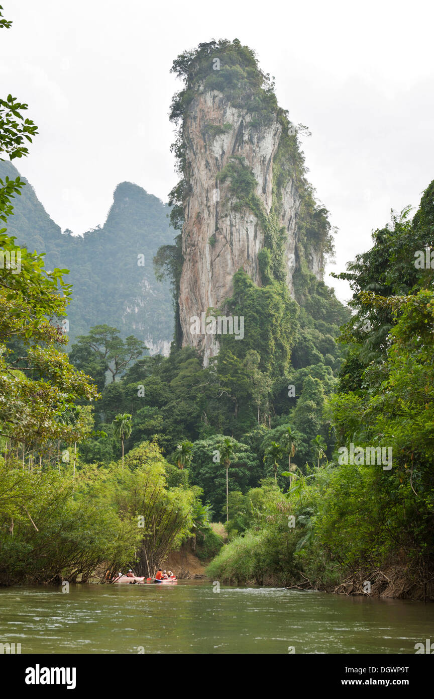 Kajakfahrer auf einem Fluss durch den Dschungel, Karstlandschaft mit einer Pinnacle Rock überragt sie rudern Stockfoto