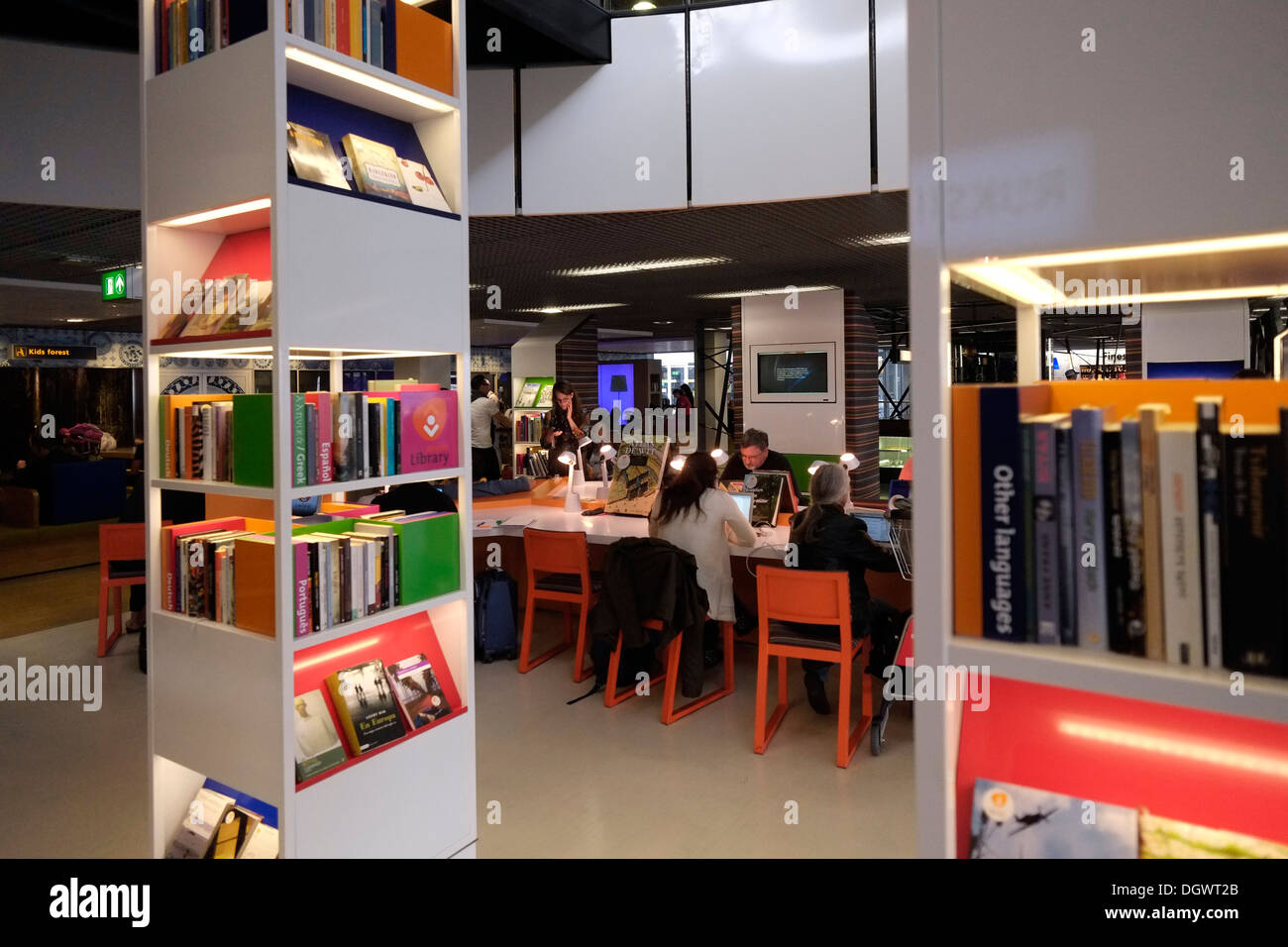 Passagiere lesen Bücher an einem kostenlosen Bibliotheksbereich, während sie auf ihren Flug am Flughafen Schiphol Amsterdam Holland warten Stockfoto