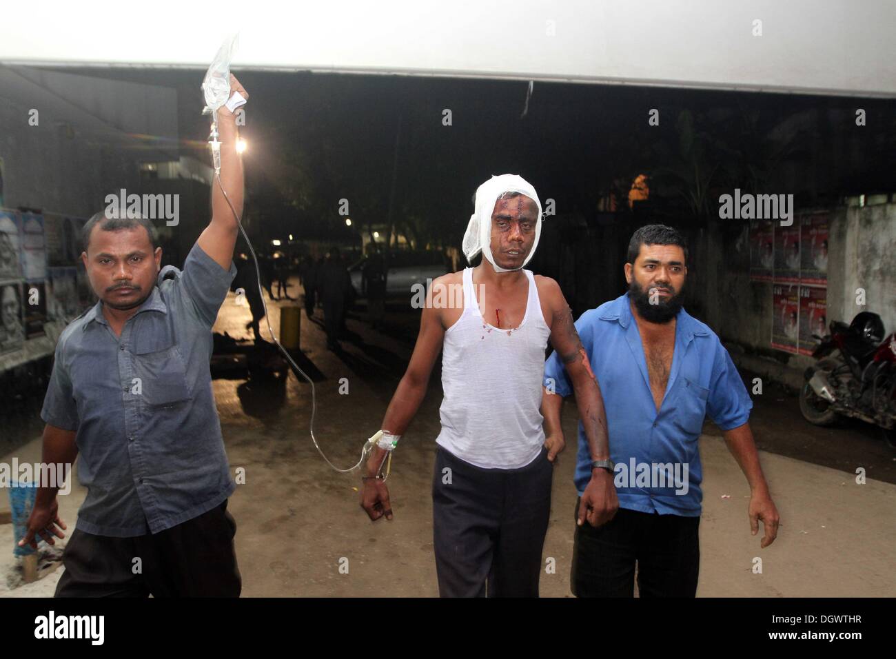 Dhaka, Bangladesch. 26 Okt, 2013. Kollege hilft Alal, ein Fahrer eines auto Rikscha, zu einem Operationssaal in Dhaka Medical College Hospital, nachdem er in einem Bombenattentat in Dhaka, Oktober 26, 2013 verletzt wurde. Pro-Streik Aktivisten warfen rohe Bomben, mutwillig zerstört und das Feuer auf mindestens 13 Fahrzeuge und mehr als 50 Menschen in Dhaka verletzt wurden. Bangladesh Nationalist Party (BNP) und die Verbündeten für drei Tag landesweite Streik von Sonntag genannt wird, eine geschäftsführende Regierung fordert, die lokalen Medien berichtet. Stockfoto
