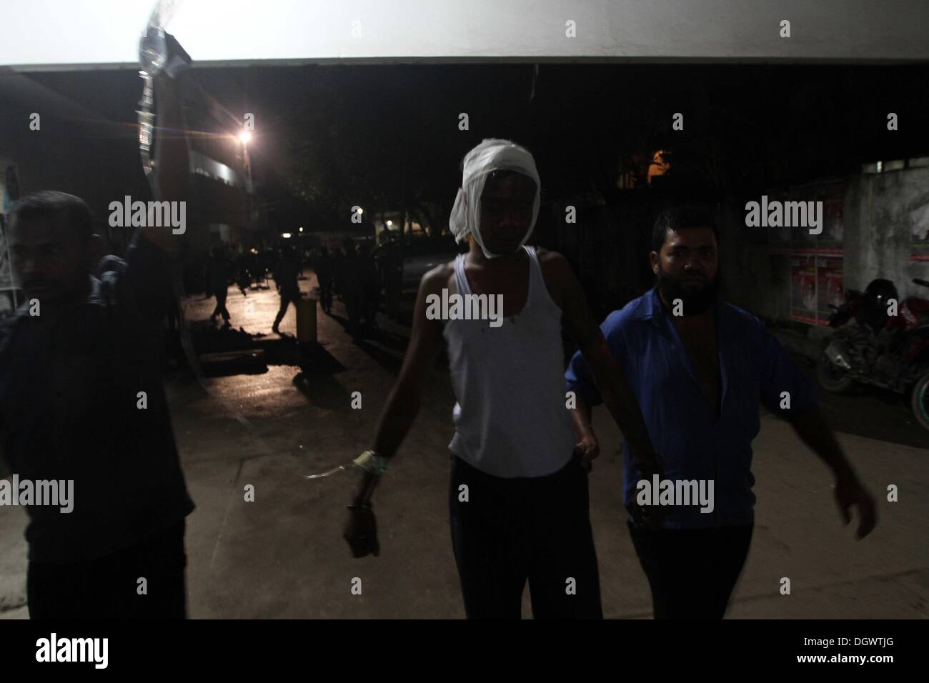 Dhaka, Bangladesch. 26 Okt, 2013. Kollege hilft Alal, ein Fahrer eines auto Rikscha, zu einem Operationssaal in Dhaka Medical College Hospital, nachdem er in einem Bombenattentat in Dhaka, Oktober 26, 2013 verletzt wurde. Pro-Streik Aktivisten warfen rohe Bomben, mutwillig zerstört und das Feuer auf mindestens 13 Fahrzeuge und mehr als 50 Menschen in Dhaka verletzt wurden. Bangladesh Nationalist Party (BNP) und die Verbündeten für drei Tag landesweite Streik von Sonntag genannt wird, eine geschäftsführende Regierung fordert, die lokalen Medien berichtet. Stockfoto