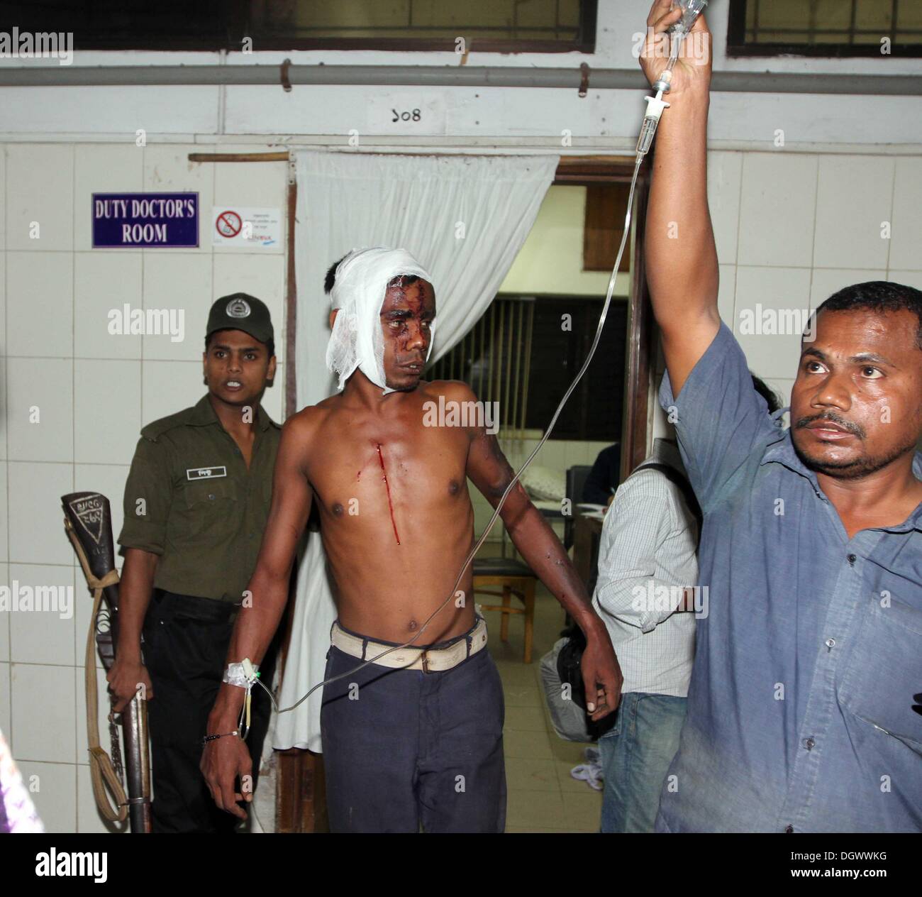 Dhaka, Bangladesch. 26 Okt, 2013. Ein Kollege hilft Alal, ein Fahrer eines auto Rikscha, zu einem Operationssaal in Dhaka Medical College Hospital, nachdem er in einem Bombenattentat in Dhaka, Oktober 26, 2013 verletzt wurde. Pro-Streik Aktivisten warfen rohe Bomben, mutwillig zerstört und das Feuer auf mindestens 13 Fahrzeuge und mehr als 50 Menschen in Dhaka verletzt wurden. Bangladesh Nationalist Party (BNP) und die Verbündeten für drei Tag landesweite Streik von Sonntag genannt wird, eine geschäftsführende Regierung fordert, die lokalen Medien berichtet. Stockfoto