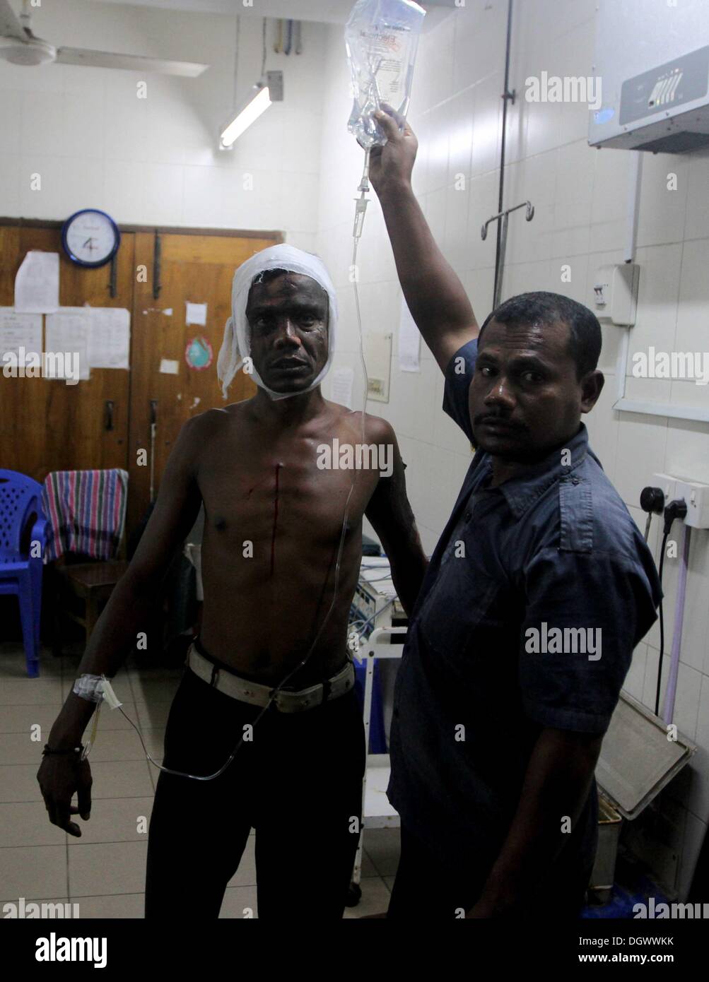 Dhaka, Bangladesch. 26 Okt, 2013. Ein Kollege hilft Alal, ein Fahrer eines auto Rikscha, zu einem Operationssaal in Dhaka Medical College Hospital, nachdem er in einem Bombenattentat in Dhaka, Oktober 26, 2013 verletzt wurde. Pro-Streik Aktivisten warfen rohe Bomben, mutwillig zerstört und das Feuer auf mindestens 13 Fahrzeuge und mehr als 50 Menschen in Dhaka verletzt wurden. Bangladesh Nationalist Party (BNP) und die Verbündeten für drei Tag landesweite Streik von Sonntag genannt, fordern Sie eine geschäftsführende Regierung, lokale Medien berichteten Stockfoto