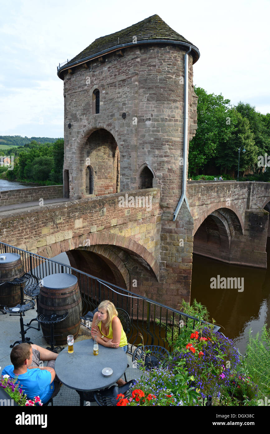 Paar sitzt an der mittelalterlichen Monnow Bridge aus dem 13. Jahrhundert, Monmouth, Monmouthshire, Wales (Cymru), Großbritannien Stockfoto