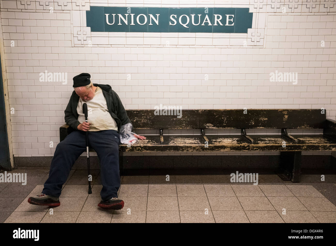 Alter Mann schlafen auf einer Bank im Union Square u-Bahnstation in New York City Stockfoto