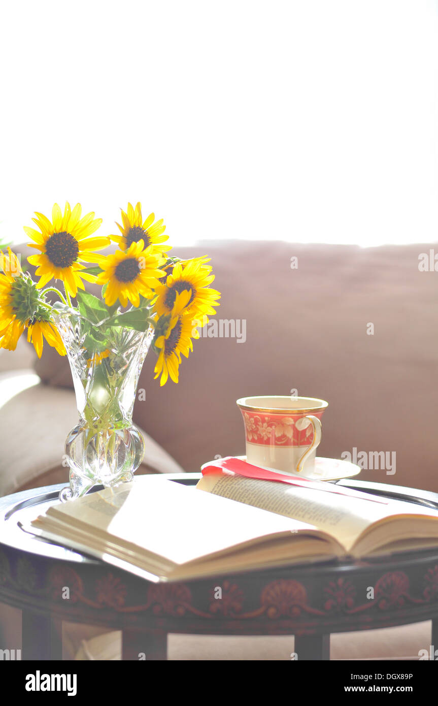 Ein offenes Buch mit einer Tasse Tee und einem Sofa im Hintergrund Stockfoto