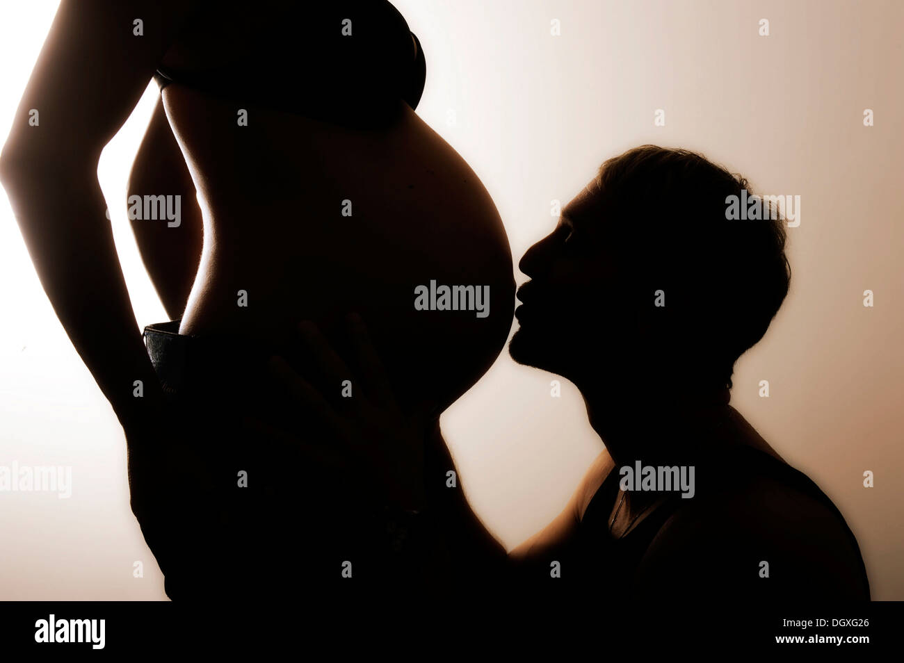 Mann den schwangeren Bauch seiner Frau zu küssen, silhouette Stockfoto