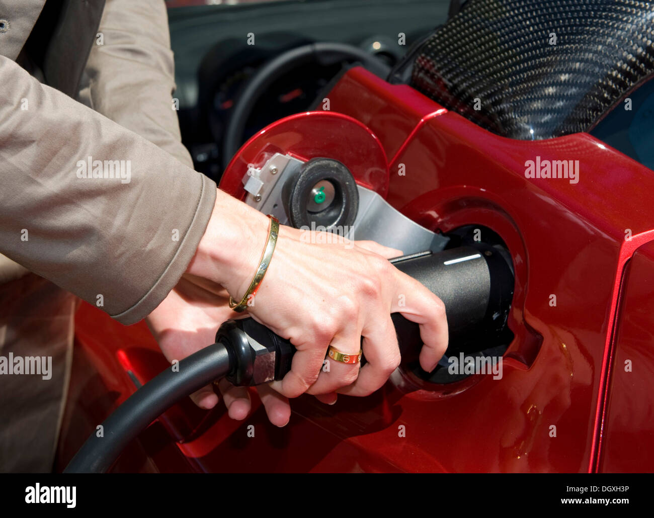 Eine Frau, die "Auftanken" eine Tesla Roadster batteriebetriebenes Elektrofahrzeug an einer Ladestation, Starnberg, Bayern Stockfoto