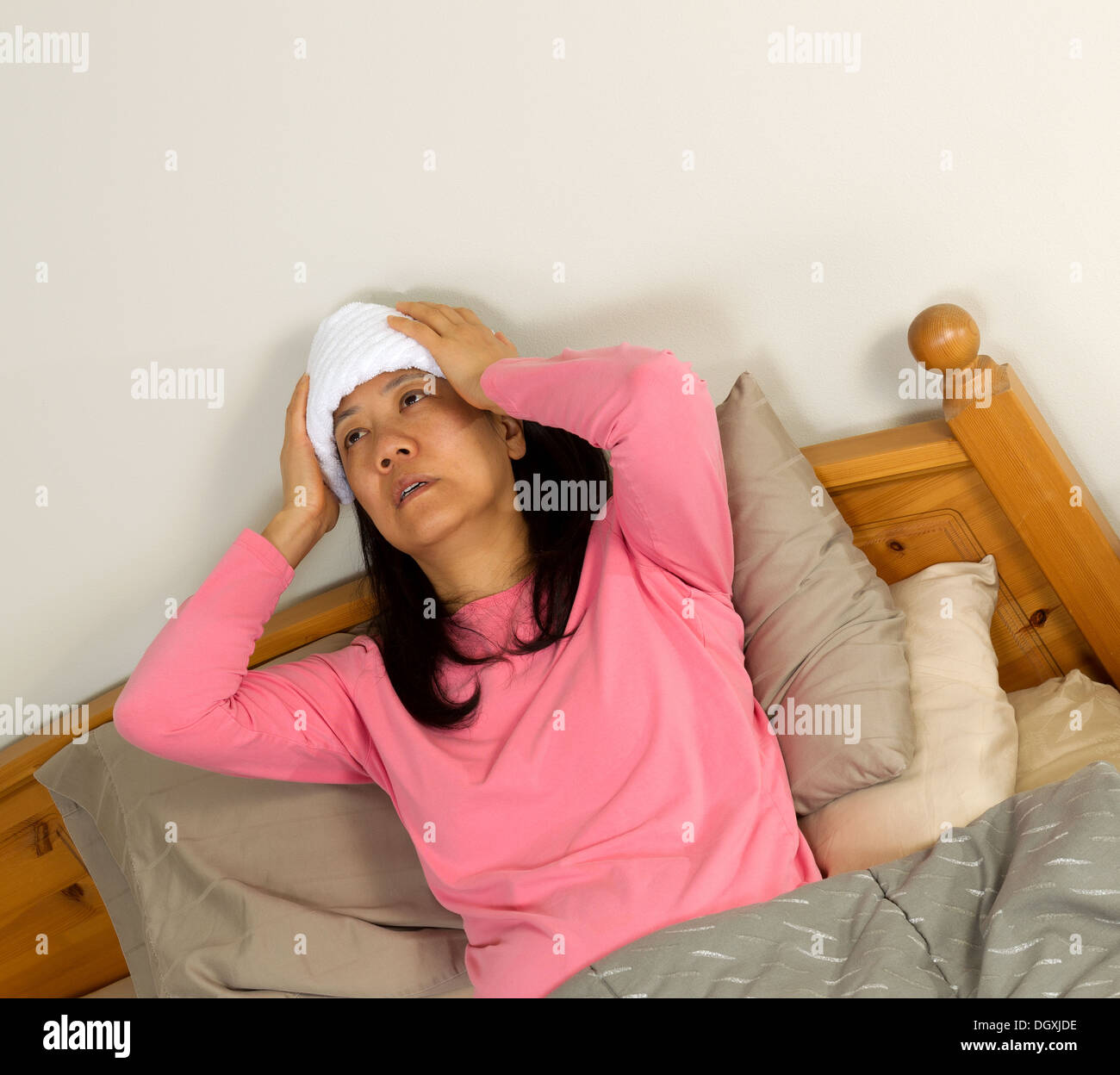 Foto von Reife Frau Fieber zu behandeln, indem Sie Waschlappen an ihrer  Stirn halten, beim liegen im Bett Stockfotografie - Alamy