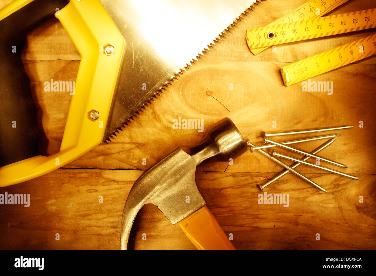 Hammer, Nägel, Lineal und Säge auf Holz Stockfoto