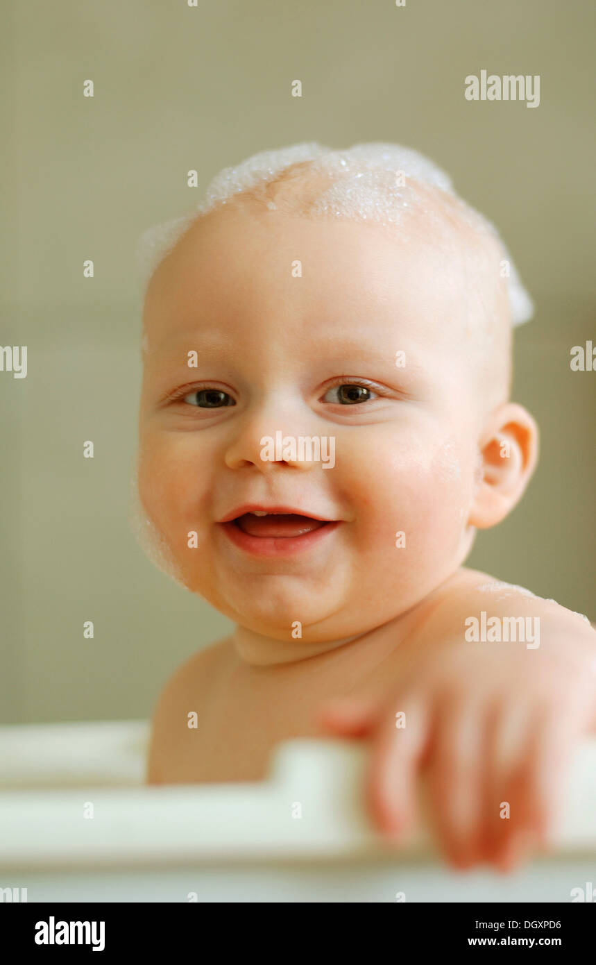 Baby in einem Bad mit Schaum auf dem Kopf Stockfoto