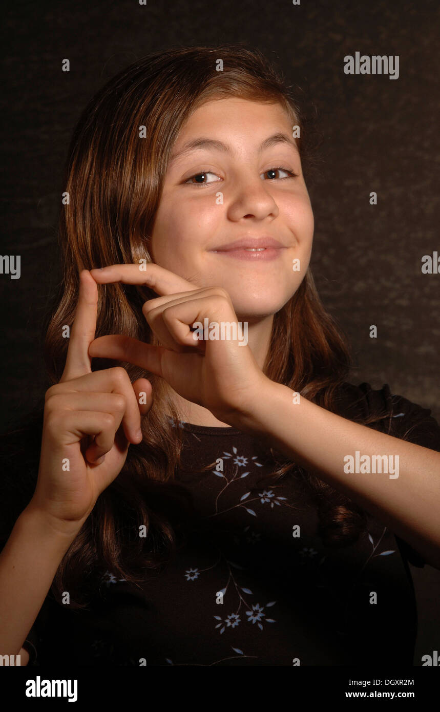Lächelnde Teenager-Mädchen machen Zeichensprache Stockfoto