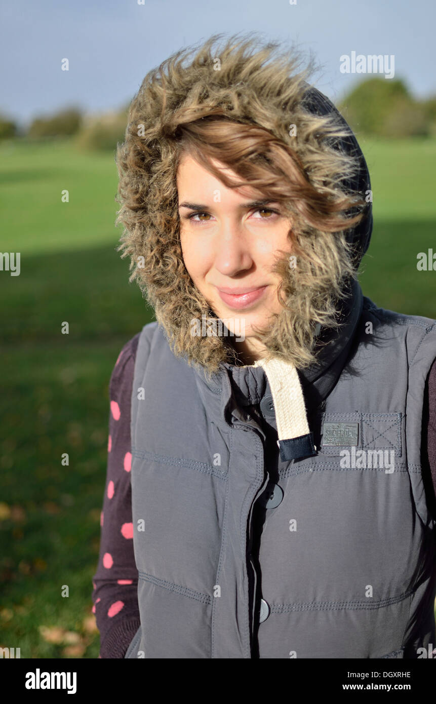 Junge Frau Lächeln auf den Lippen tragen ein Gilet mit pelzigen Kapuze Stockfoto