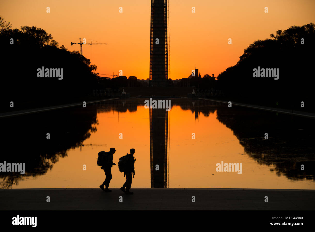 Lincoln Memorial Reflecting Pool Soldaten Training Washington DC | WASHINGTON D.C., Vereinigte Staaten — Zwei Soldaten mit Rucksäcken gehen bei Sonnenaufgang am Lincoln Memorial Reflecting Pool vorbei, das Washington Monument spiegelt sich im Wasser hinter ihnen wider, ein Hinweis auf die frühen Morgen Trainingsroutinen, die unter Dienstmitgliedern in der Nähe der Hauptstadt üblich sind. Der Pool, der sich über etwa 2.028 Fuß (618 m) in Richtung des Obelisken erstreckt, wurde 1922-1923 als Teil von Henry Bacons Entwurf für das Lincoln Memorial gebaut. Stockfoto