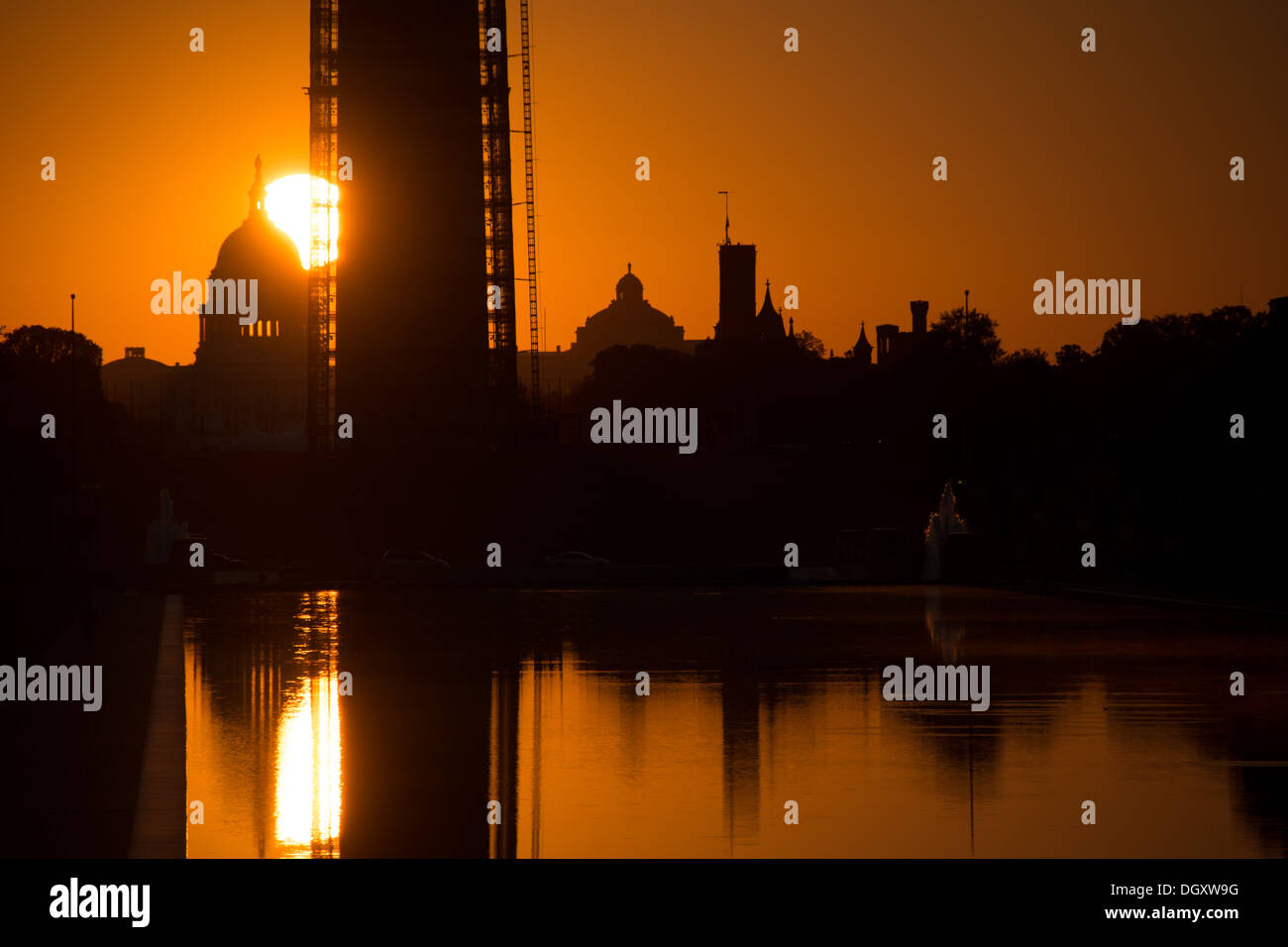 WASHINGTON DC, USA - Die aufgehende Sonne sehr niedrig am Horizont hinter dem Washington Monument und einen reflektierenden Pool in Washington DC. Stockfoto