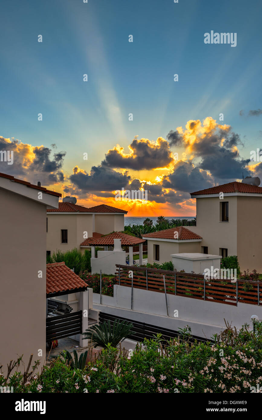 Sonnenuntergang mit Sonnenstrahlen über luxuriöse Strandvillen zu vermieten auf Zypern Stockfoto