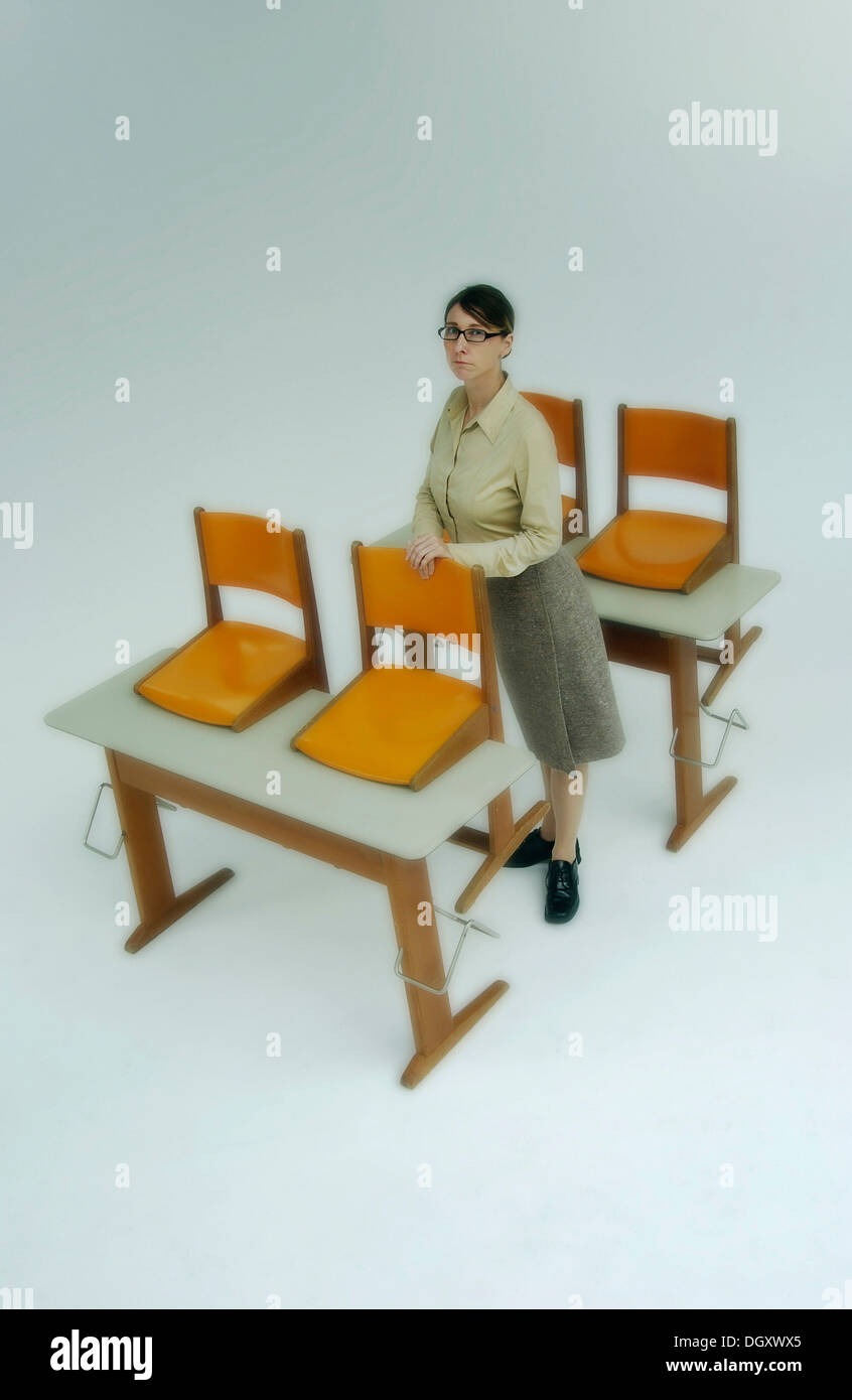 Strenge Lehrerin am alten Schulbänke mit orange Stühle stehen Stockfoto