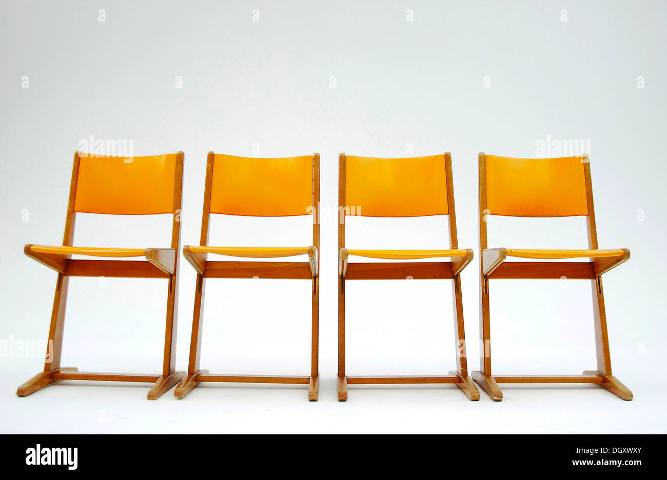 Vier alte orange Schule Stühle nebeneinander stehen Stockfoto
