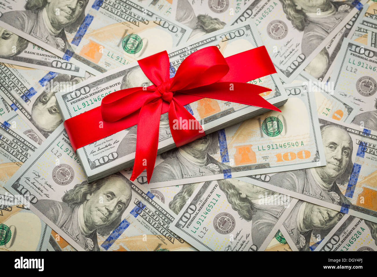 Stapel von neu gestalteten US Hundert Dollar Bills Geschenk verpackt in roter Schleife. Stockfoto