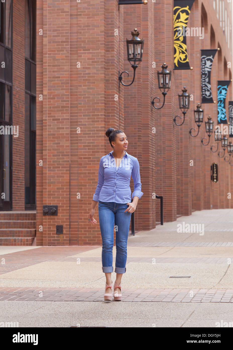 Junge Afroamerikanerin Wandern neben Backsteingebäude Stockfoto