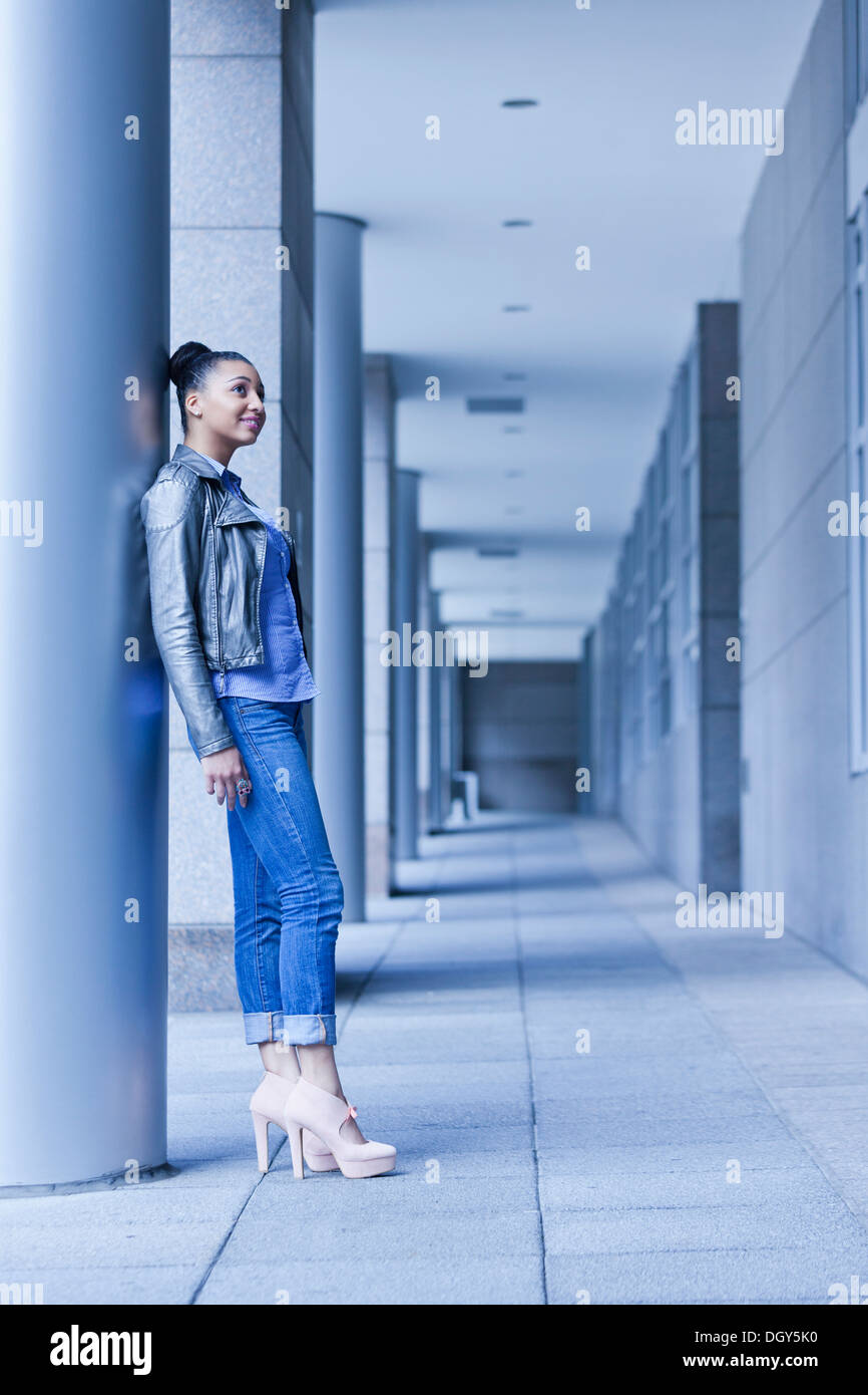 Junge Afro-amerikanische Frau in voller Länge, Höhenplan, stützte sich auf Gebäude Stockfoto