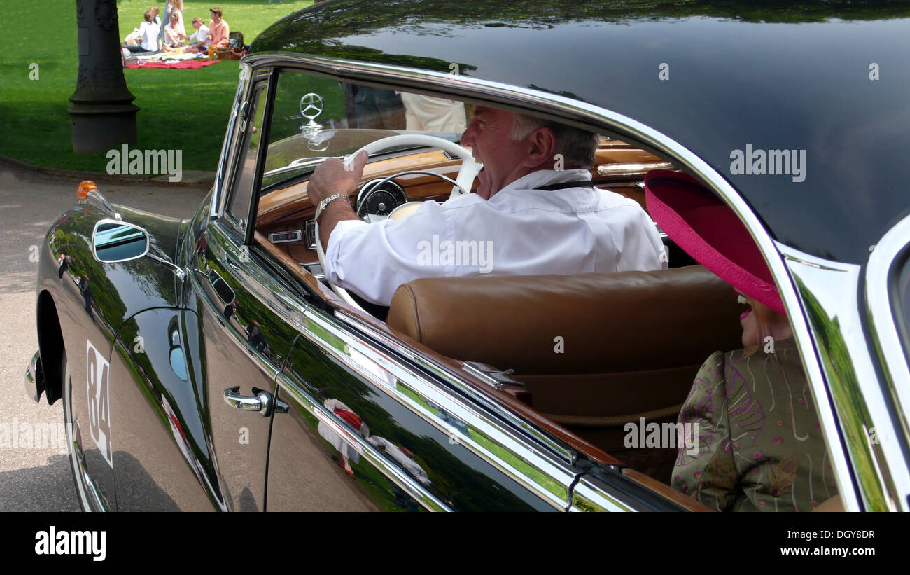 Chauffeur und elegante alte Dame mit einem rosa Hut in einem alten Mercedes Benz 300D Stockfoto