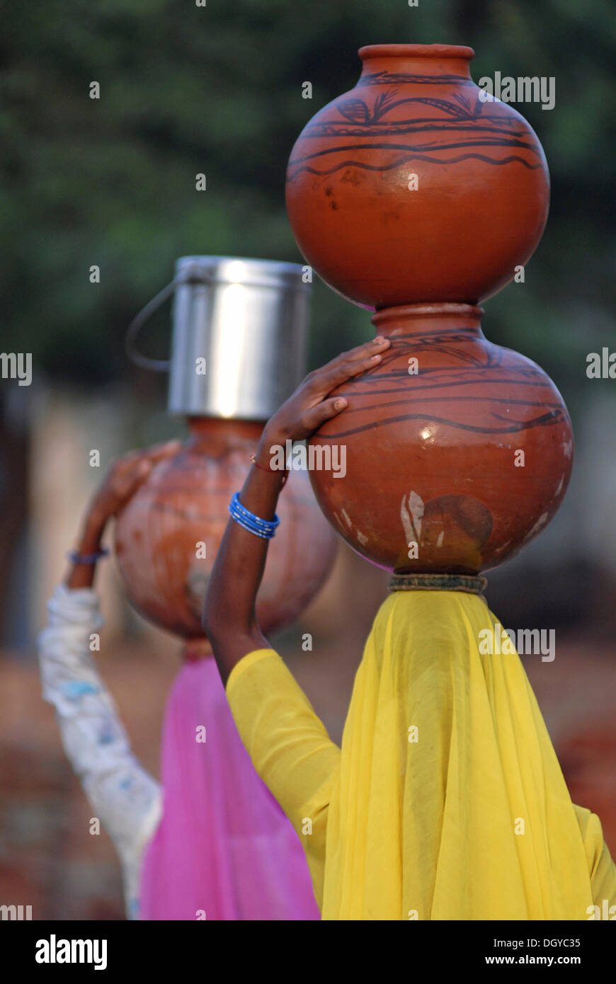 Frauen, die mit Wasser gefüllten Tontöpfen auf ihren Köpfen, Neemrana, Rajasthan, Nordindien, Indien, Asien Stockfoto