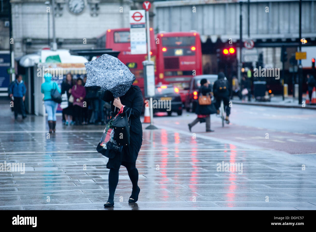 London, UK - 28. Oktober 2013: eine Frau, die London Brücke kämpft mit ihrem Schirm, wie die Stadt von dem Sturm getroffen wird. Der Sturm, genannt St. Jude, brachte das windigste Wetter Großbritannien seit 1987 getroffen.  Bildnachweis: Piero Cruciatti/Alamy Live-Nachrichten Stockfoto