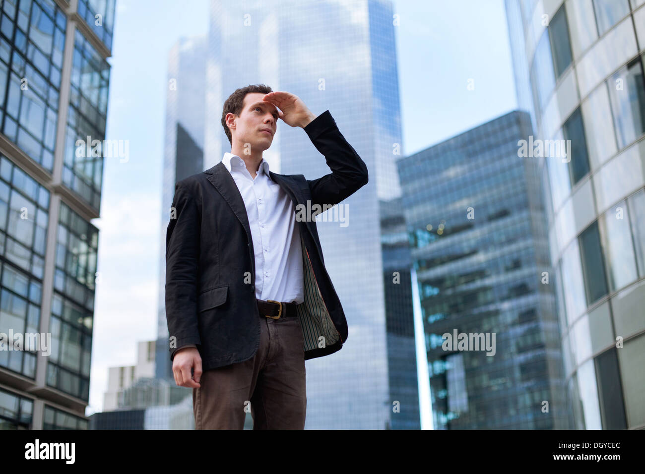 junger Geschäftsmann freut sich auf Wolkenkratzer-Hintergrund Stockfoto
