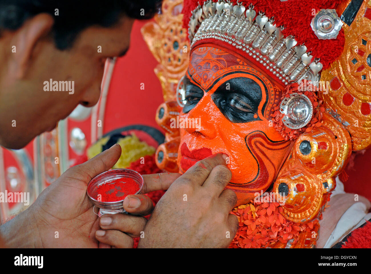 Malen das Gesicht der Theyyam Performer, Vorbereitung für ein Ritual, in der Nähe von Kasargod, North Kerala Süd-Indien, Asien Stockfoto