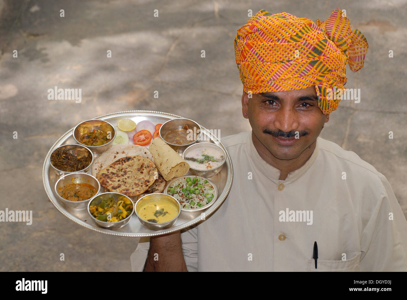Rajasthani Thali serviert auf einem silbernen Tablett, getragen von Kellner mit Turban, Narain Niwas Heritage Hotel, Jaipur, Rajasthan Stockfoto