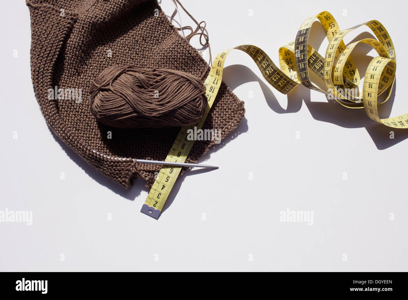 Ein Stück stricken mit Wollknäuel, Klebeband und eine Stricknadel messen Stockfoto