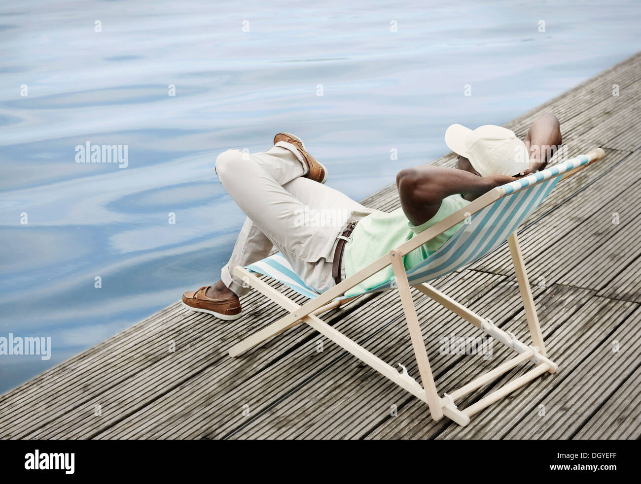 Menschen, die durch den See auf Liegestuhl entspannend Stockfoto