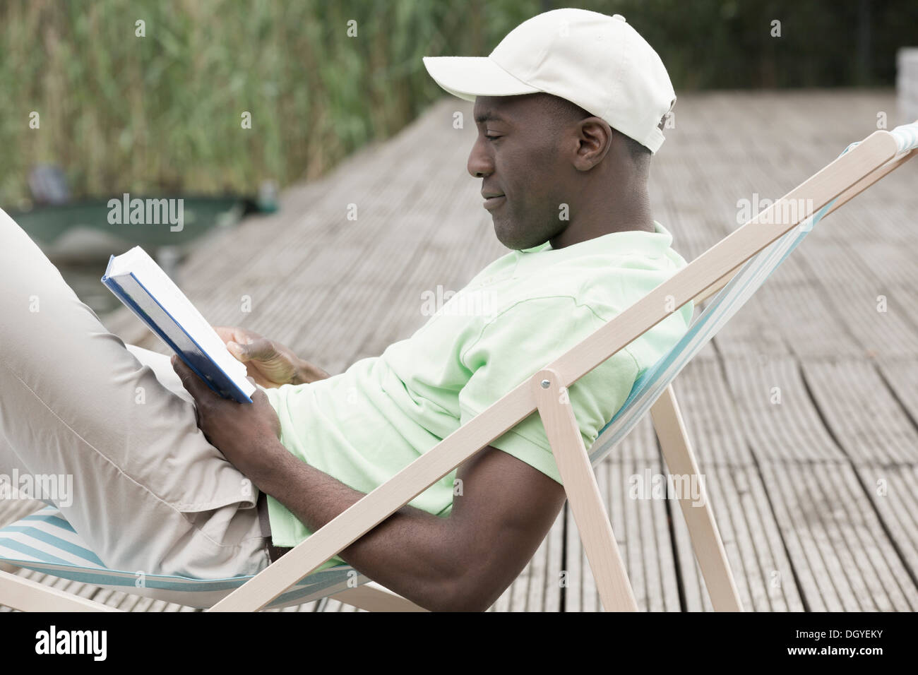 Mann, lesen und entspannen im Liegestuhl Stockfoto