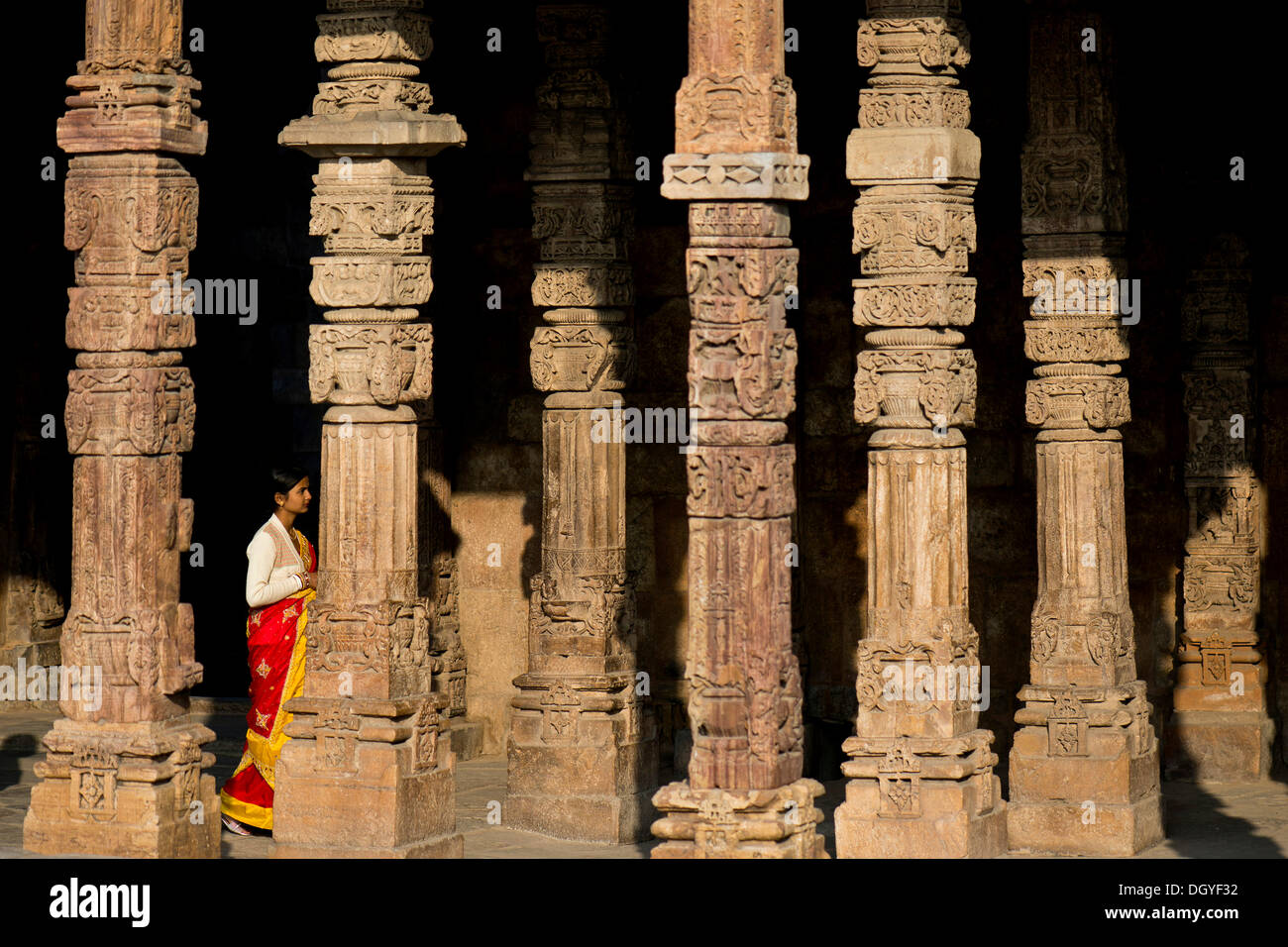 Indische Frau zu Fuß zwischen kunstvoll geschnitzten Steinsäulen, Qutb Komplex, UNESCO-Weltkulturerbe Stockfoto